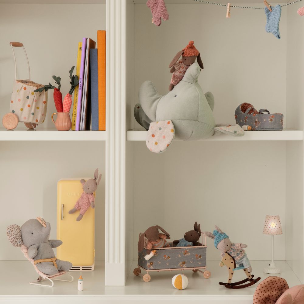Maileg children's toys and books on a shelf against a light gray wall